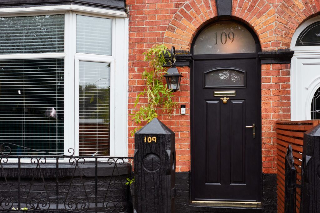 A sleek black composite door set in a brick house.