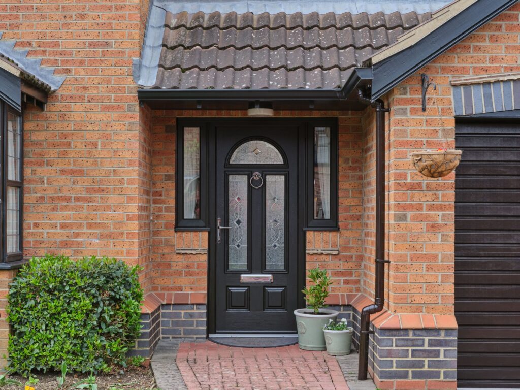 A brick house featuring a black composite front door and a garage.