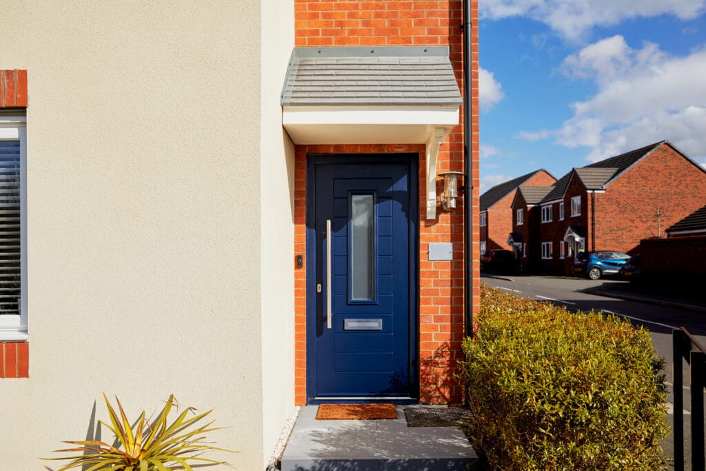 Navy blue composite front door on an orange brick house.